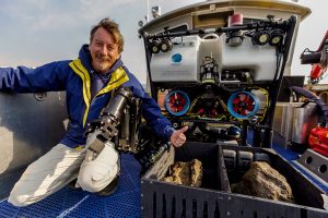 Electrical engineer and ROV pilot Dave Wright gives a thumbs up to rock samples he collected with ROV Yogi at the bottom of Yellowstone Lake. Credit: Daniel R. Rogers, GFOE